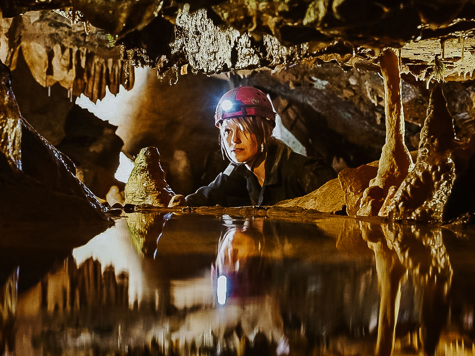 A woman caving with a red helmet on